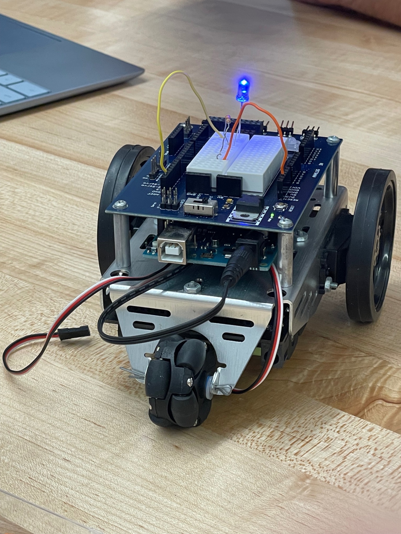 Arduino robot showing its wheeled chassis, circuit boards, breadboard, and wiring